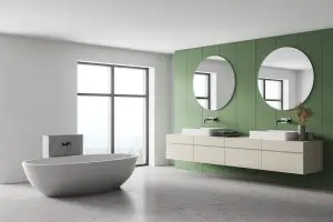 White and green bathroom with white bathtub, mirrors and marble floor