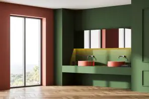 Green and pink bathroom with two sinks near window on parquet floor